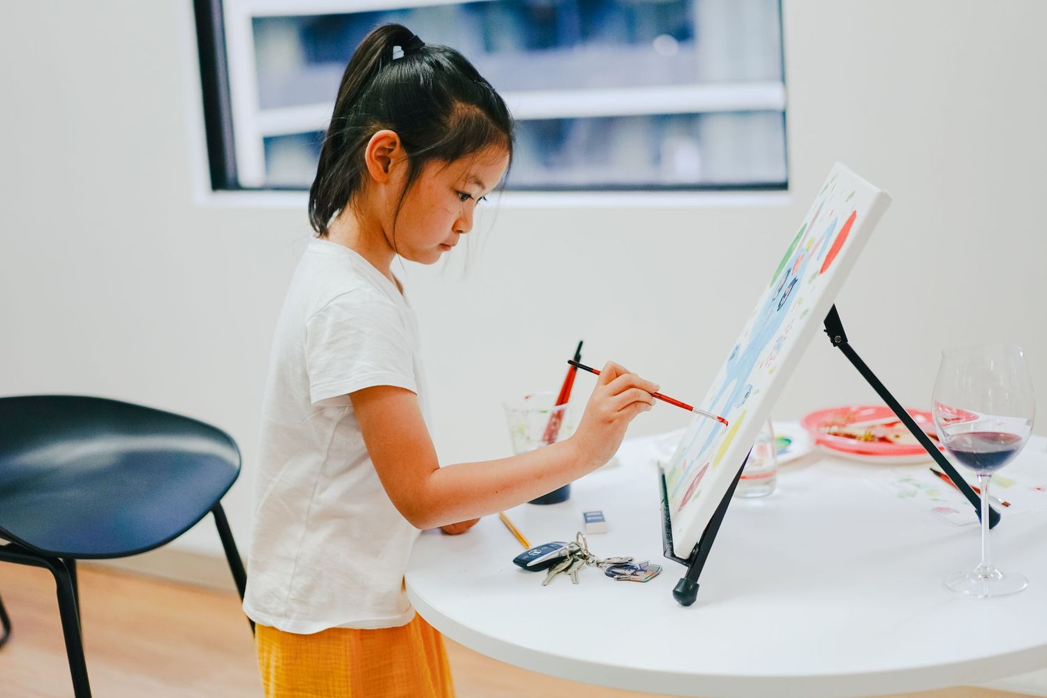 Young artist working on digital tablet at white desk in bright room.