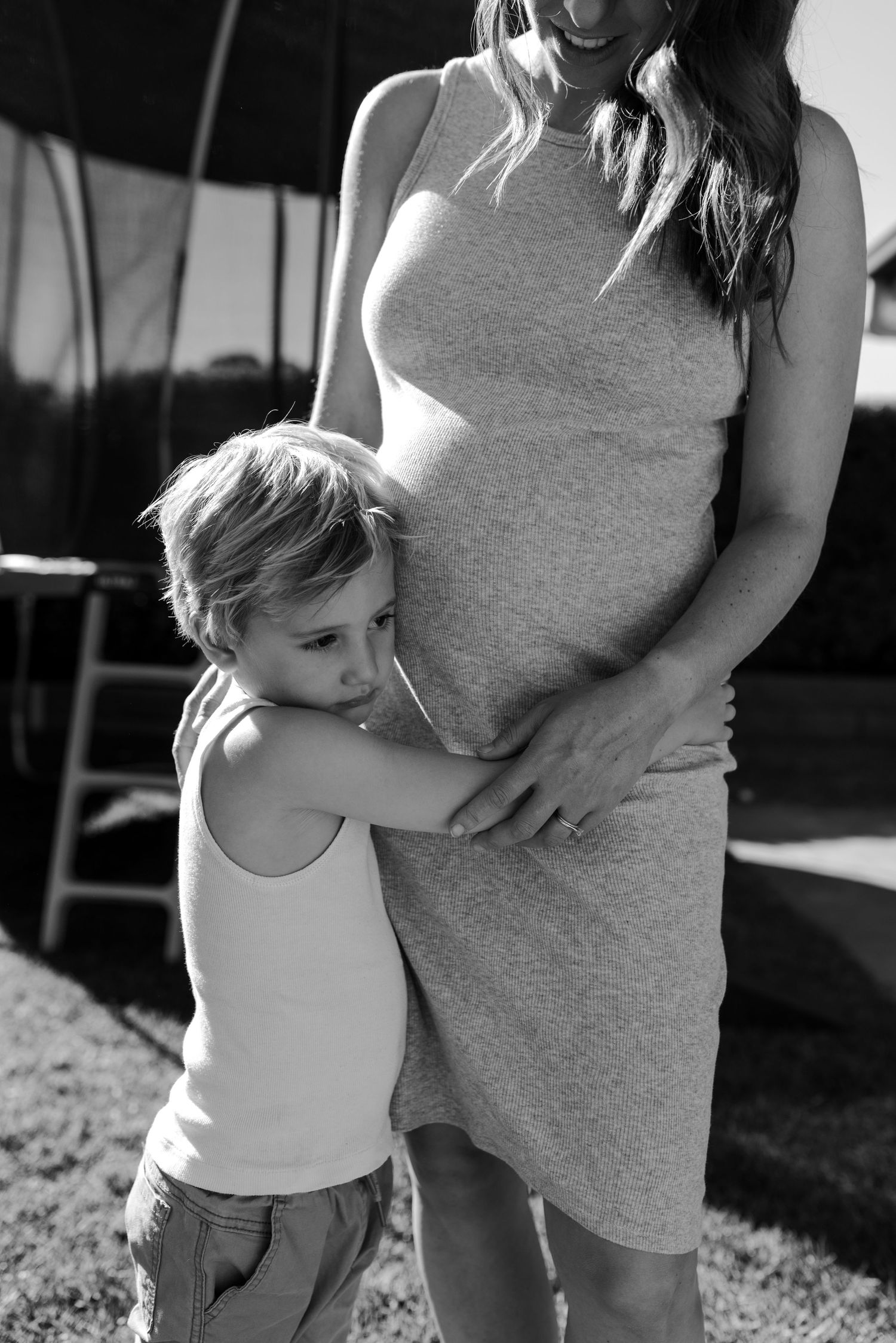 Black and white photo showing tender moment between child and expectant mother.