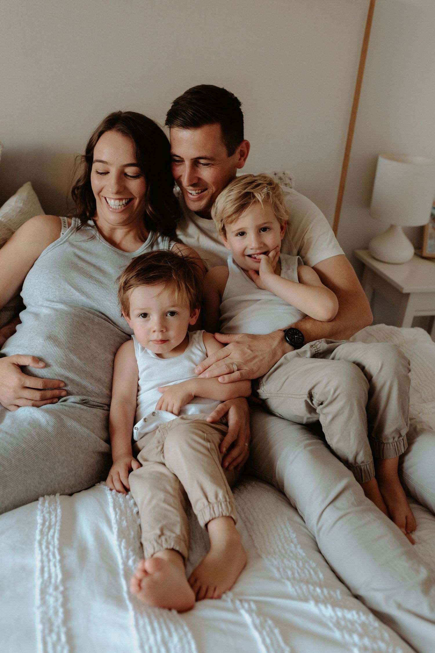 Intimate family lifestyle photos on bed showing loving moments with young child.