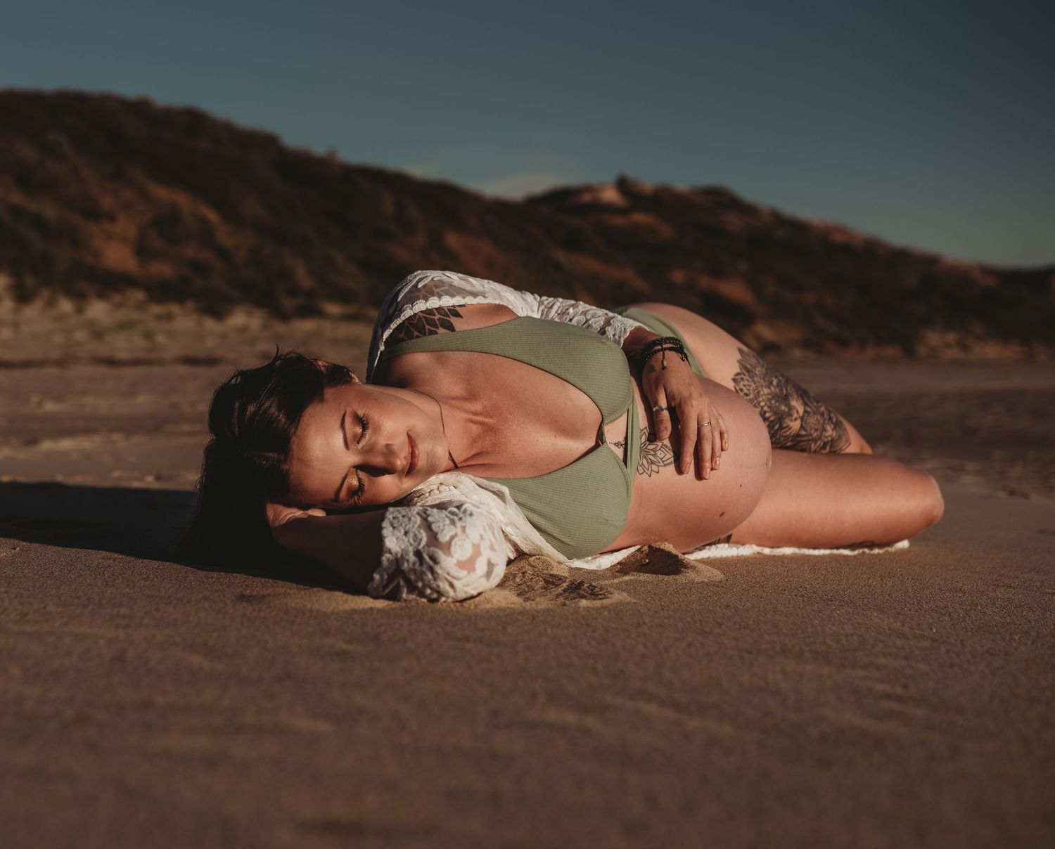 Dramatic beach maternity photography with natural lighting and coastal scenery.