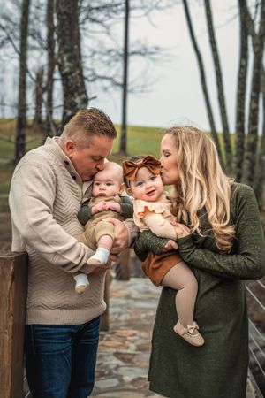 Grantparents in winter attire shares affectionate moments with two small grandchildren during an extended family photo session