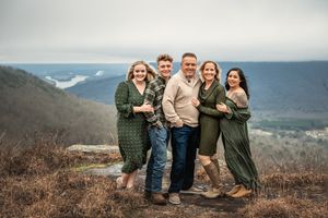 Family portrait session in casual attire on a scenic mountain overlook during autumn weather.