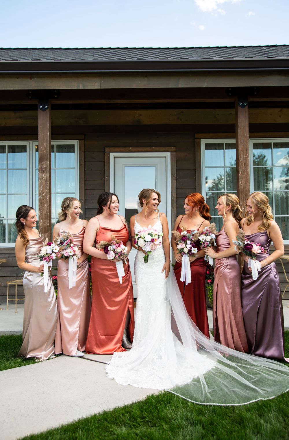 Bridal party in mix-and-match pink and burgundy dresses posing outdoors.