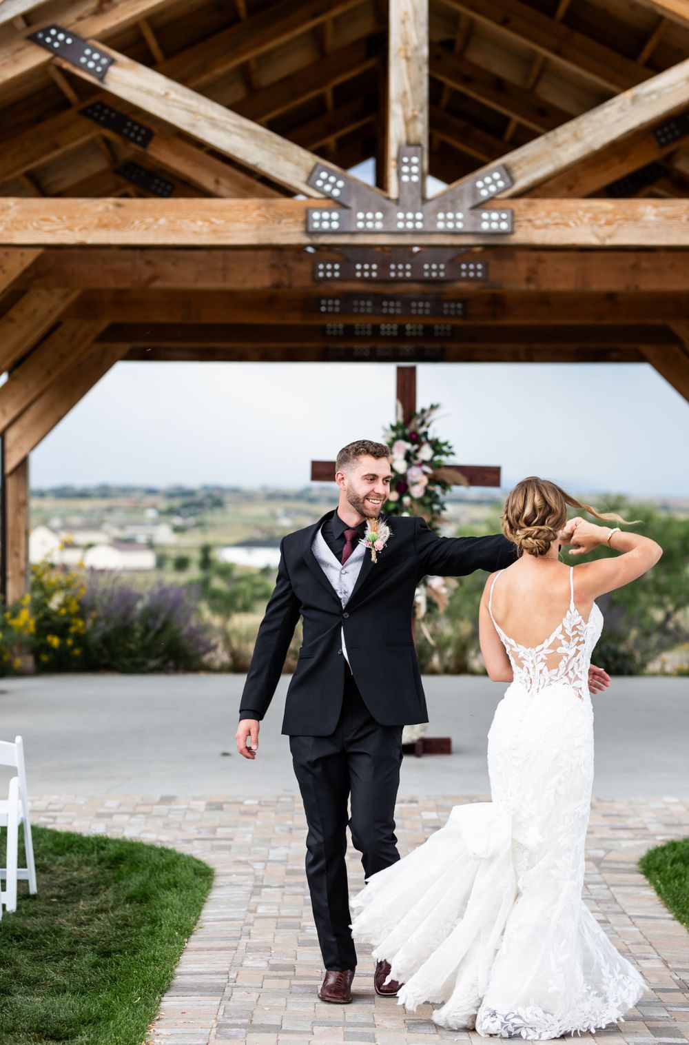 Newlyweds dance beneath a rustic wooden pavilion with mountain views in the background.