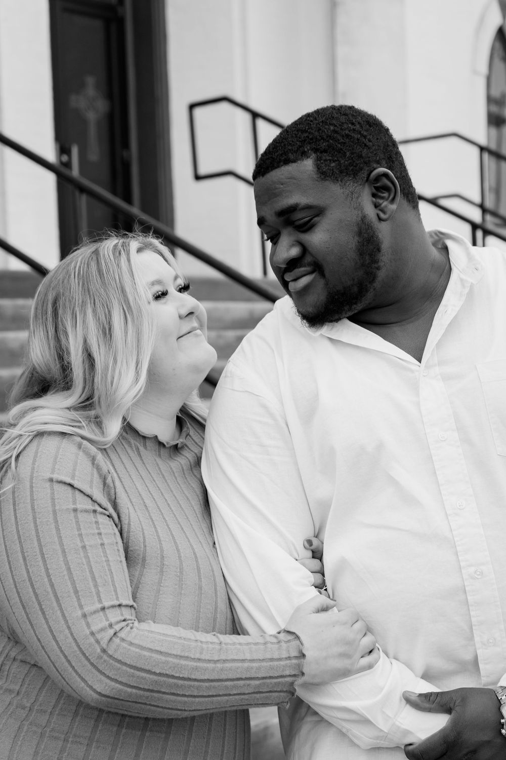 A romantic black and white portrait of a couple sharing a joyful moment on steps.