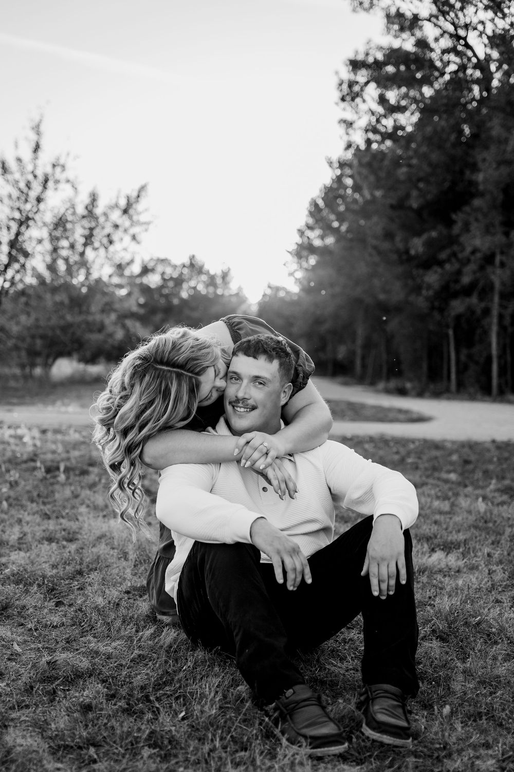 A romantic black and white photo sequence shows a couple embracing and laughing together while sitting in a grassy field.