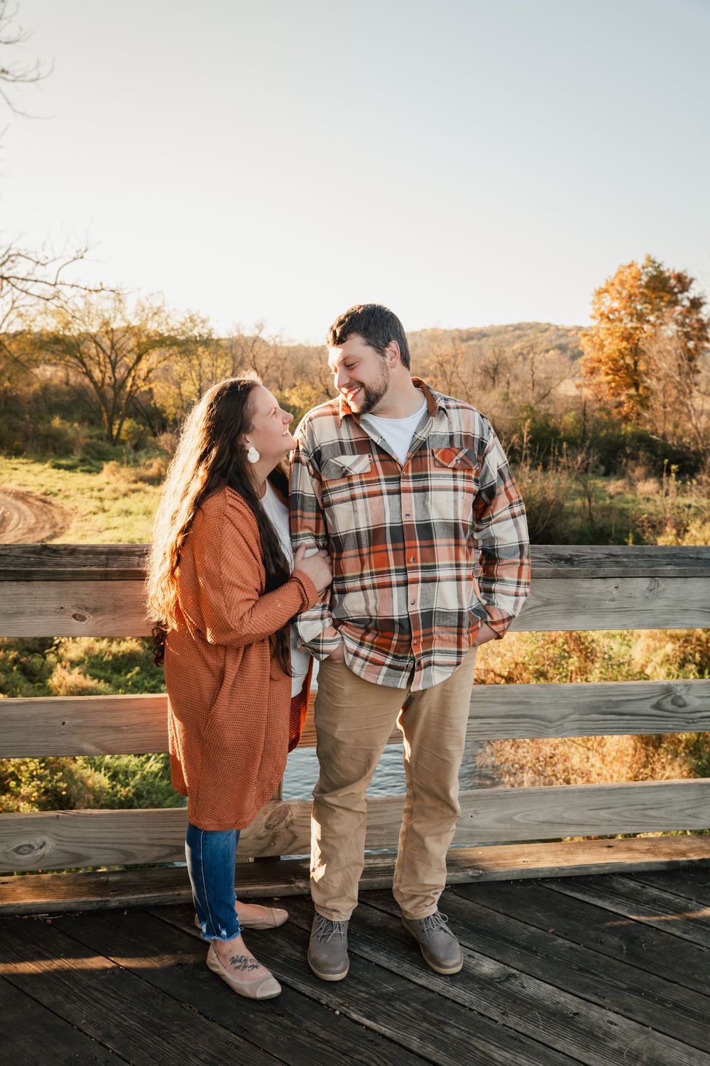 Couple in autumn attire sharing a romantic moment on a wooden deck at sunset.