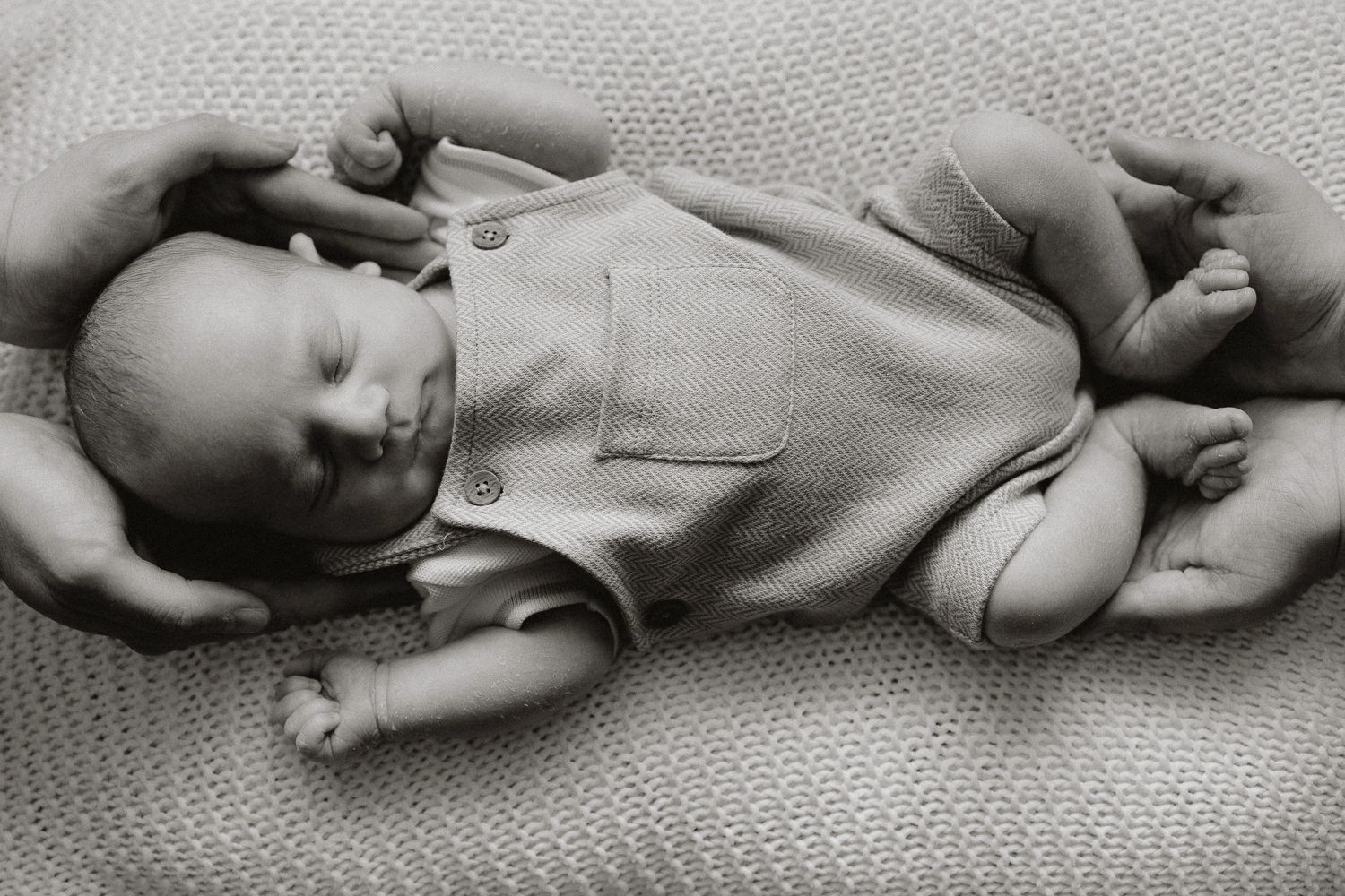 Newborn baby being held by his parents during a newborn photoshoot in Portsmouth.