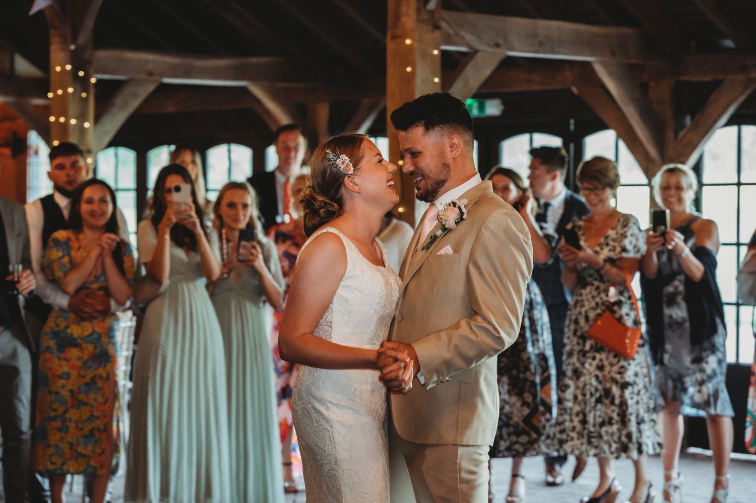 Dancing couple in formalwear share a romantic moment on the dance floor as guests in mint and floral dresses look on.