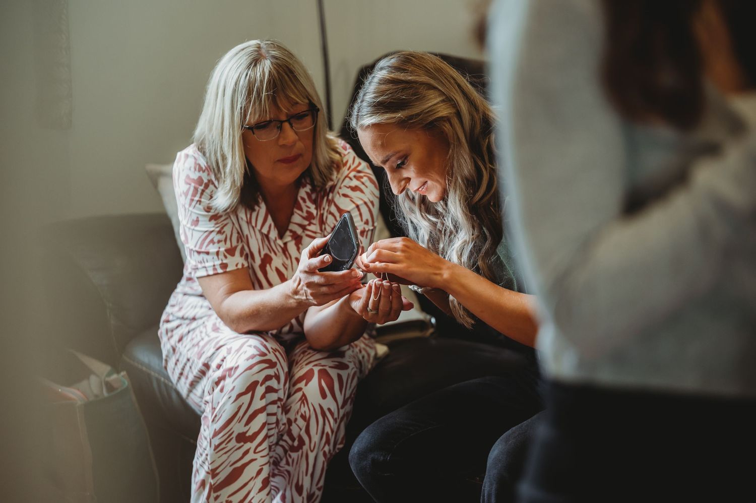Two people sitting together looking at a mobile phone while sharing a tender moment.