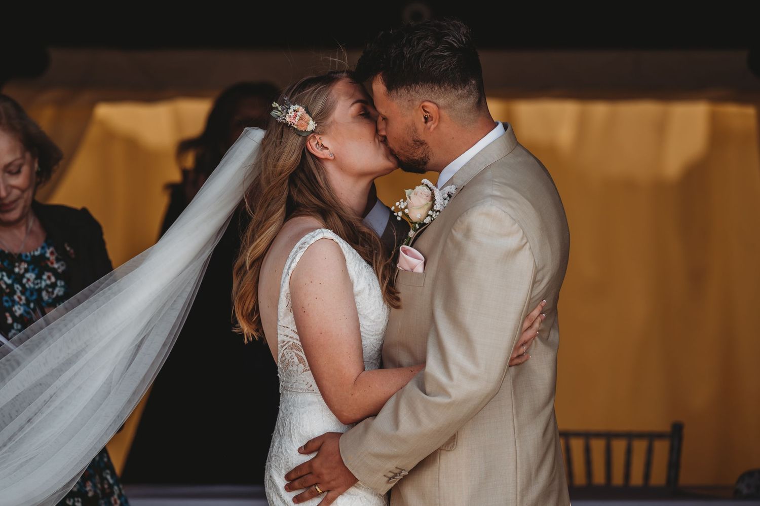 A newlywed couple shares an intimate moment during their wedding ceremony under warm indoor lighting.