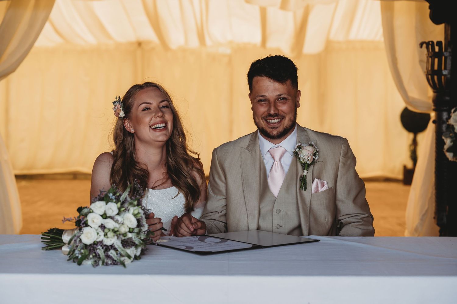A happy moment captured during document signing at a wedding ceremony with warm lighting.