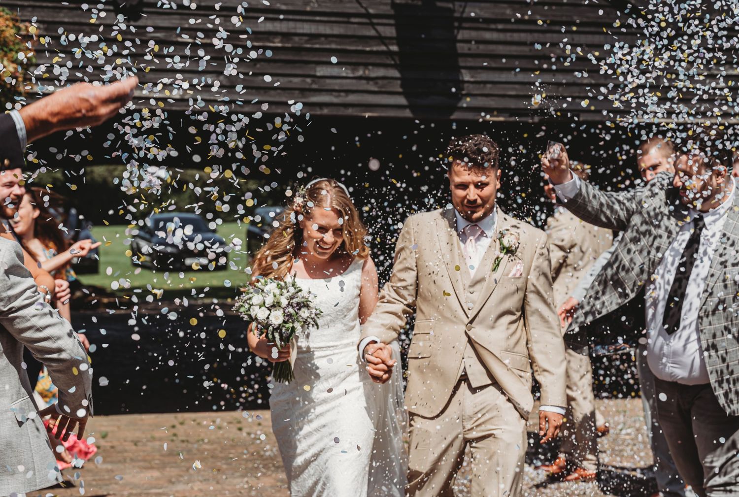 Newlyweds walk hand in hand through a shower of white confetti on their joyous wedding day.