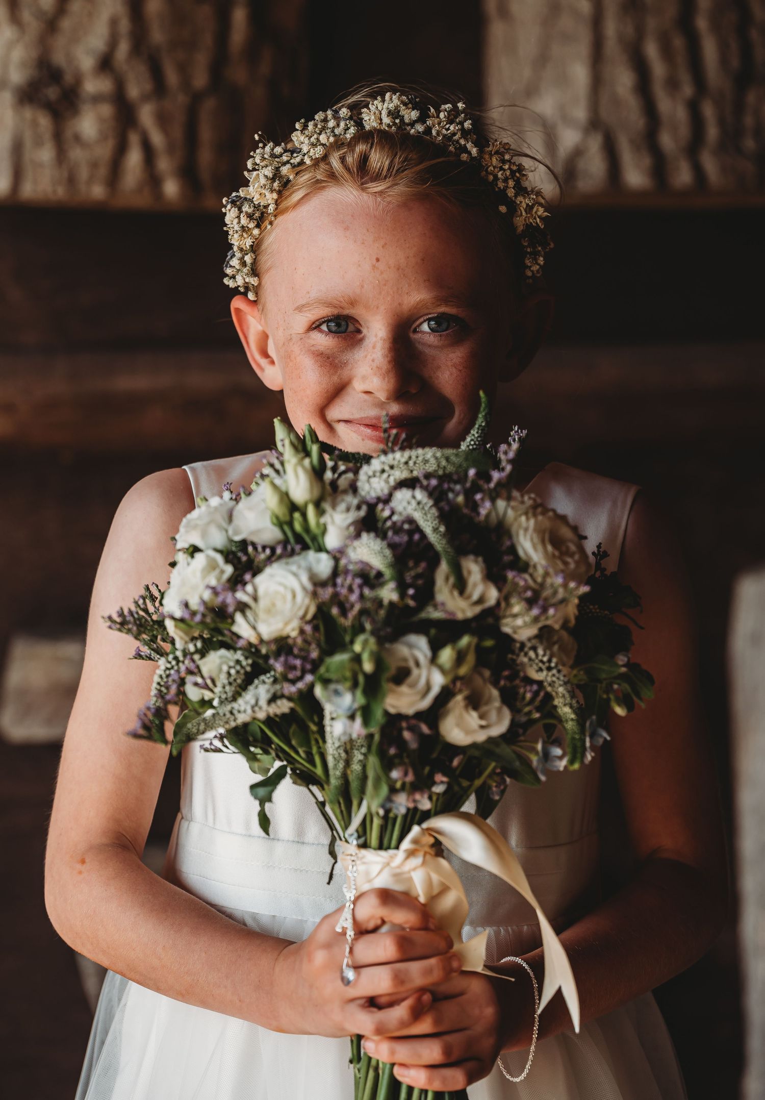 A white wedding bouquet with baby's breath crown creates a romantic rustic look against a wooden barn backdrop.