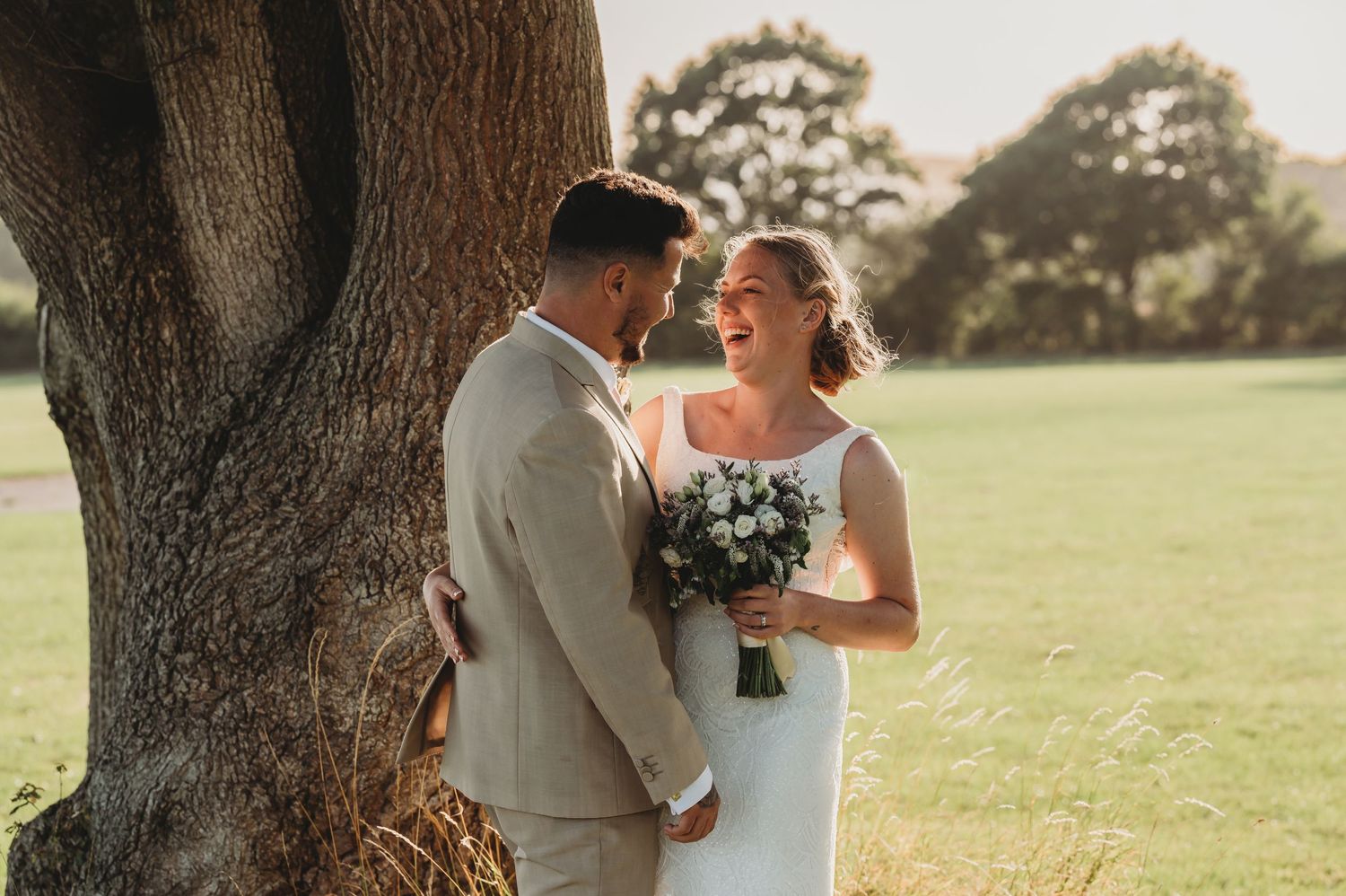 A romantic wedding moment captured by a majestic tree in soft golden sunlight.