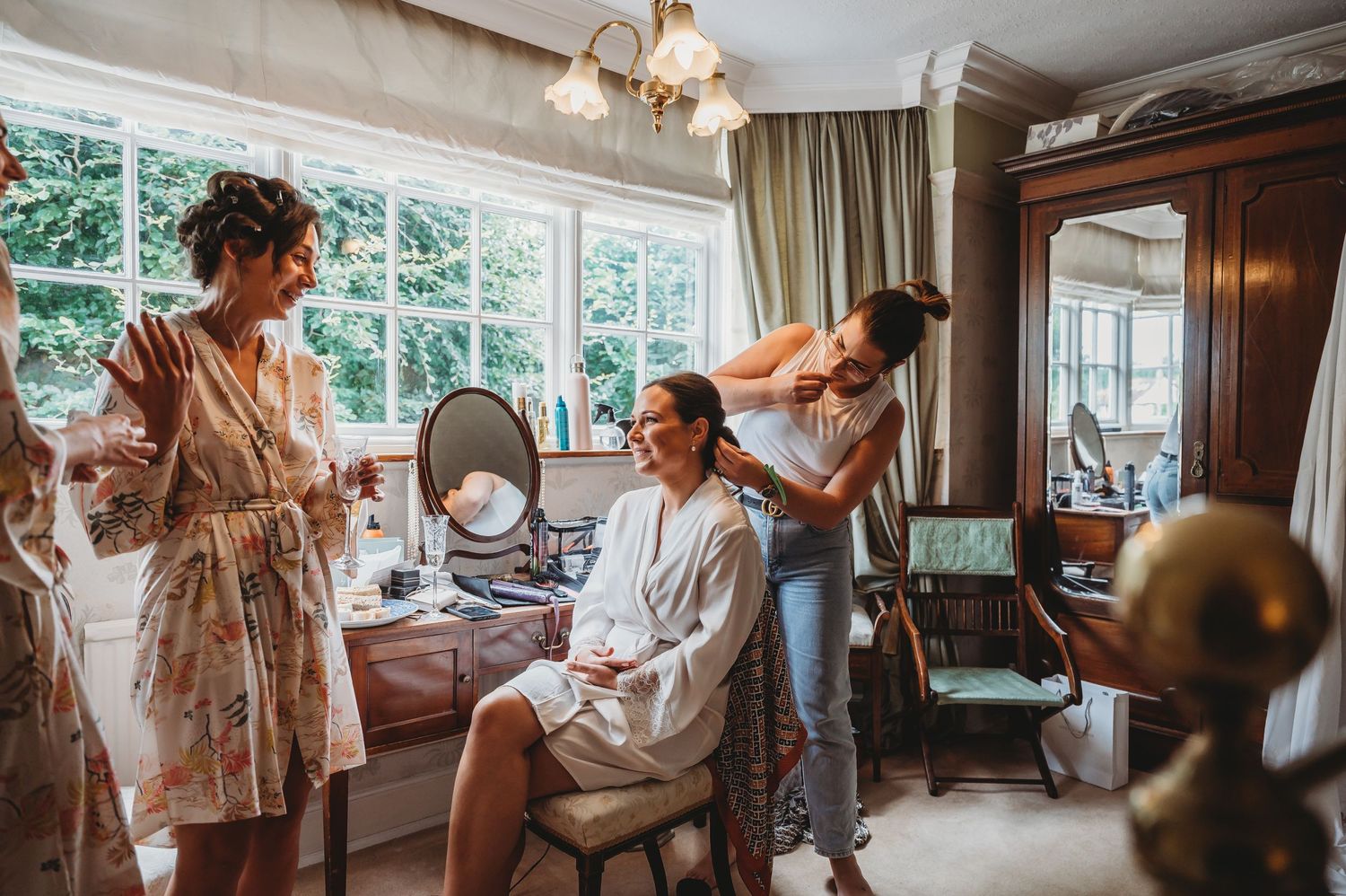 A bridal preparation scene in a sunlit room with vintage decor and a chandelier as morning preparations take place.