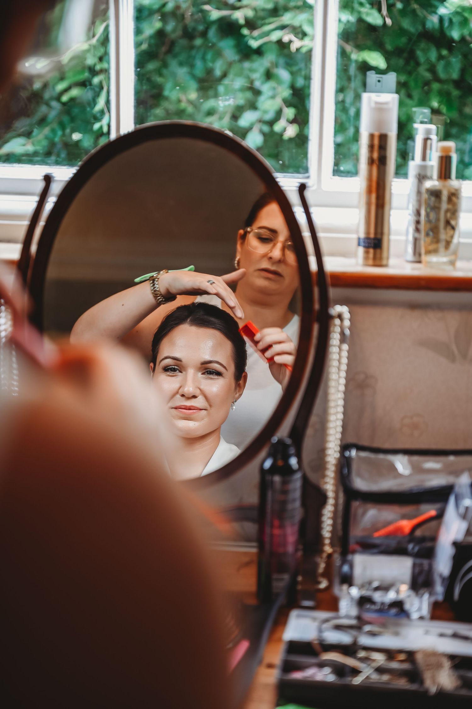 Reflection in a salon mirror shows a styling session in progress with beauty products visible on the counter.