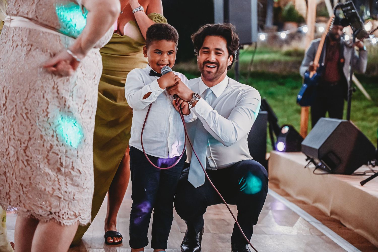 Dancing at a wedding reception outdoors with festive teal lights decorating a pink tree.
