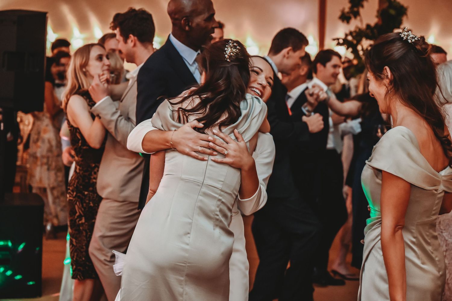Wedding reception guests dance together in an intimate moment on a dimly lit dance floor at evening celebration.
