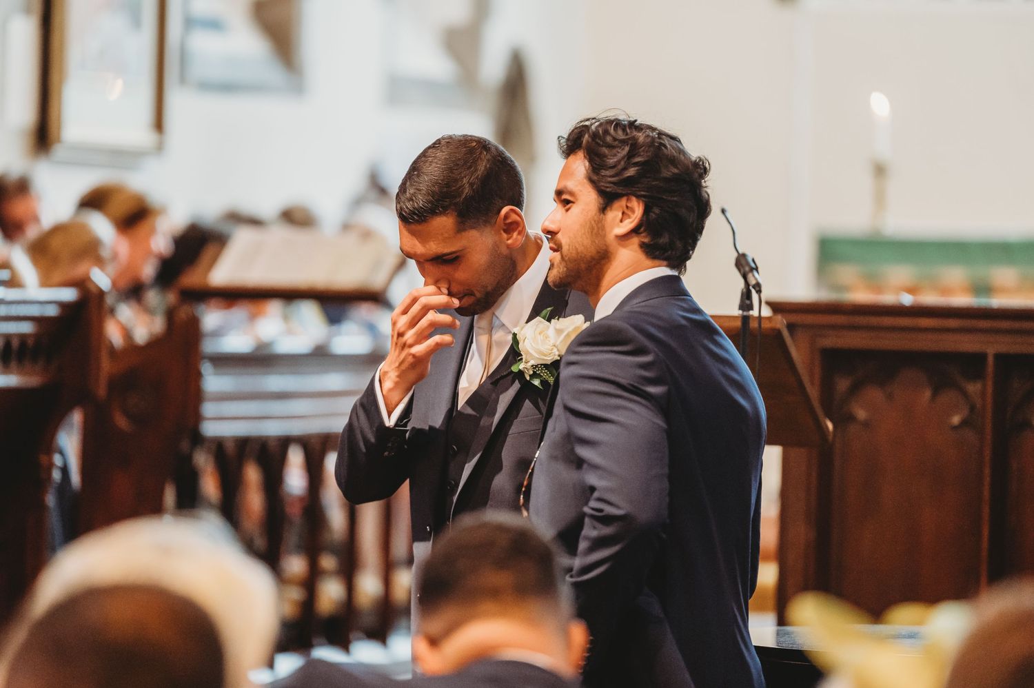 Two groomsmen sharing an emotional moment during wedding ceremony.