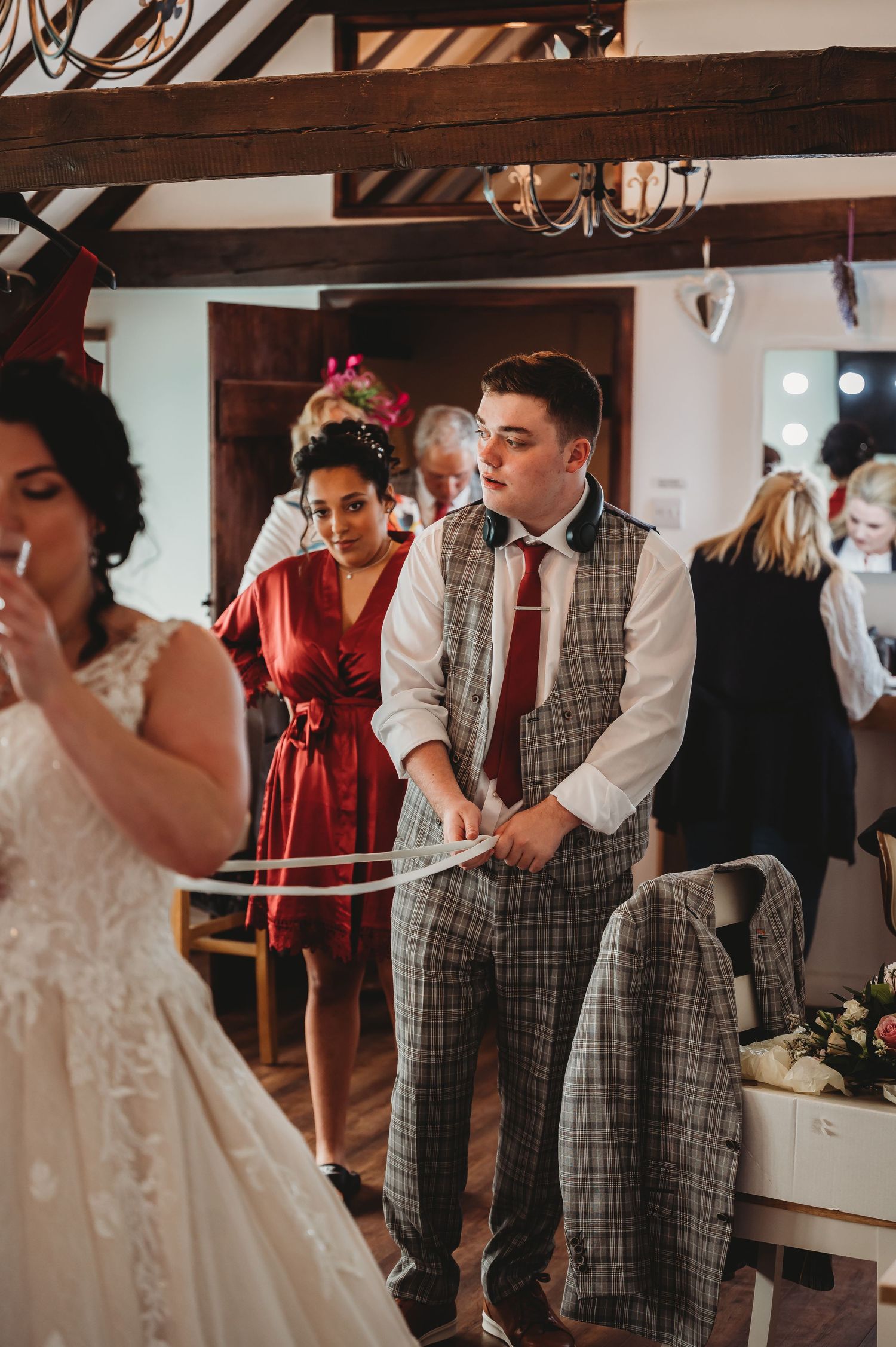 Wedding guests mingle at an indoor reception venue with exposed wooden beams and rustic decor.