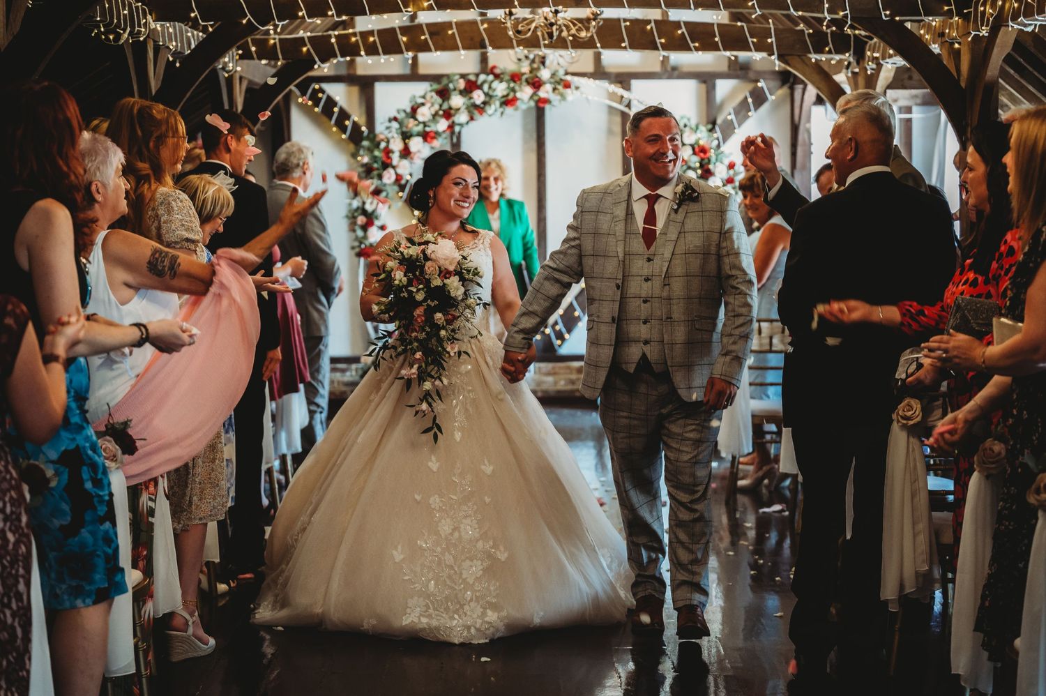 A rustic barn wedding ceremony with guests looking on as newlyweds celebrate down the aisle together.