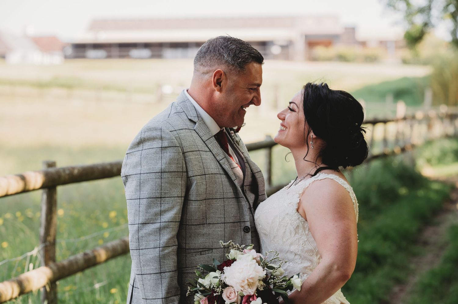 A joyful wedding couple sharing a romantic moment together in a rustic countryside setting with flowers.