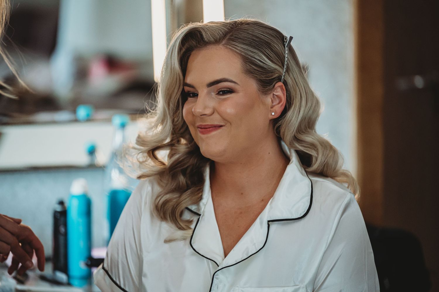 Joyful pre-wedding preparation scene with classic white robe and vintage-inspired wavy hairstyle.