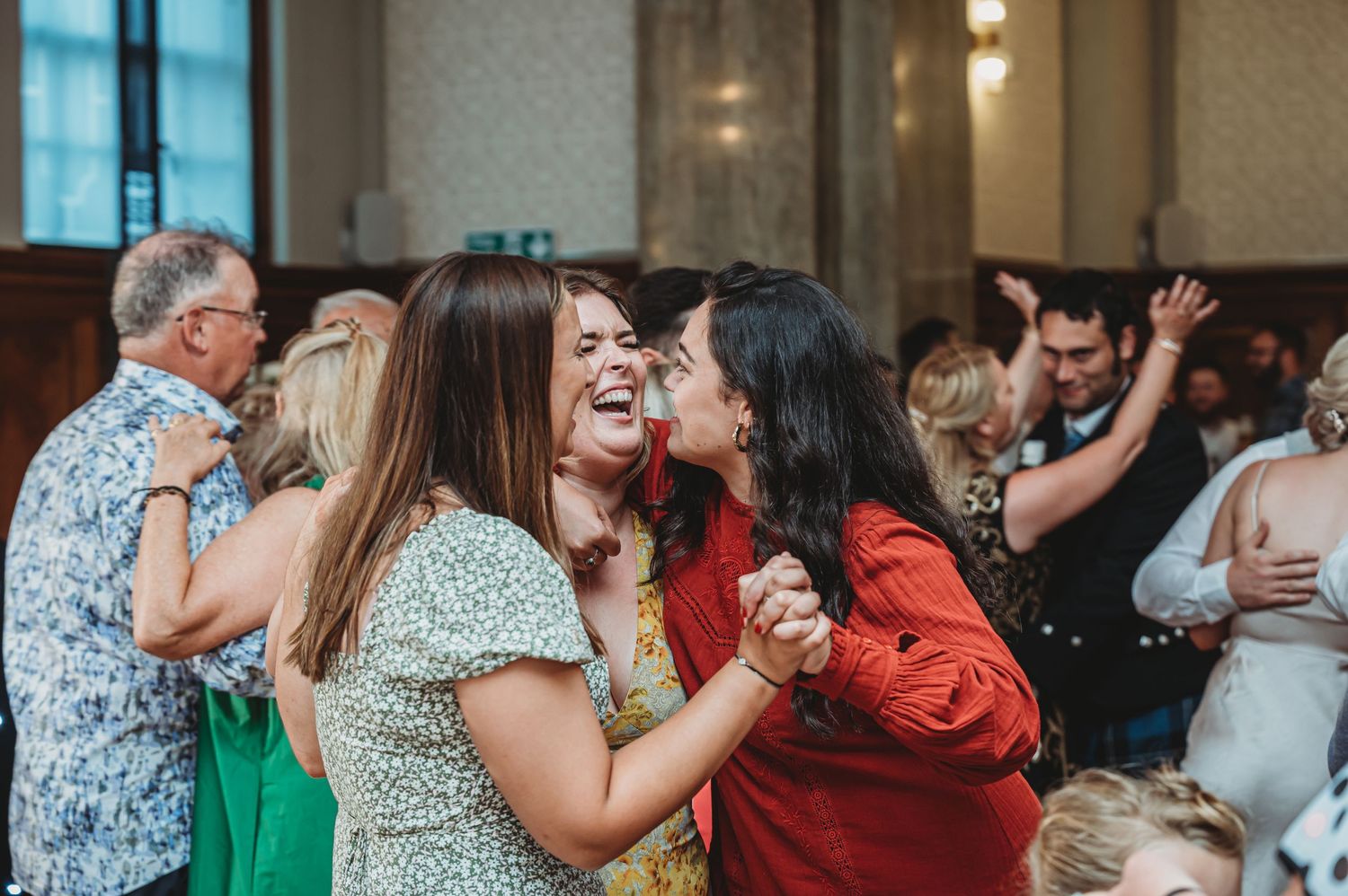 People dancing and celebrating together at a festive event with joyful expressions and laughter.