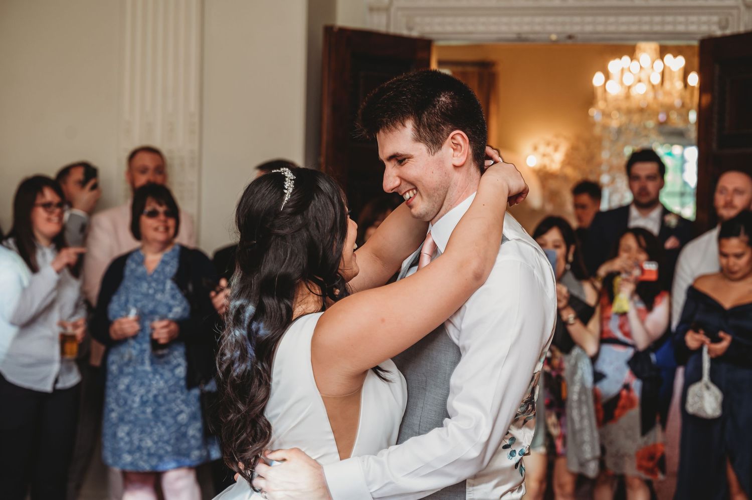 A joyful couple shares their first dance at their wedding reception while guests look on and applaud.
