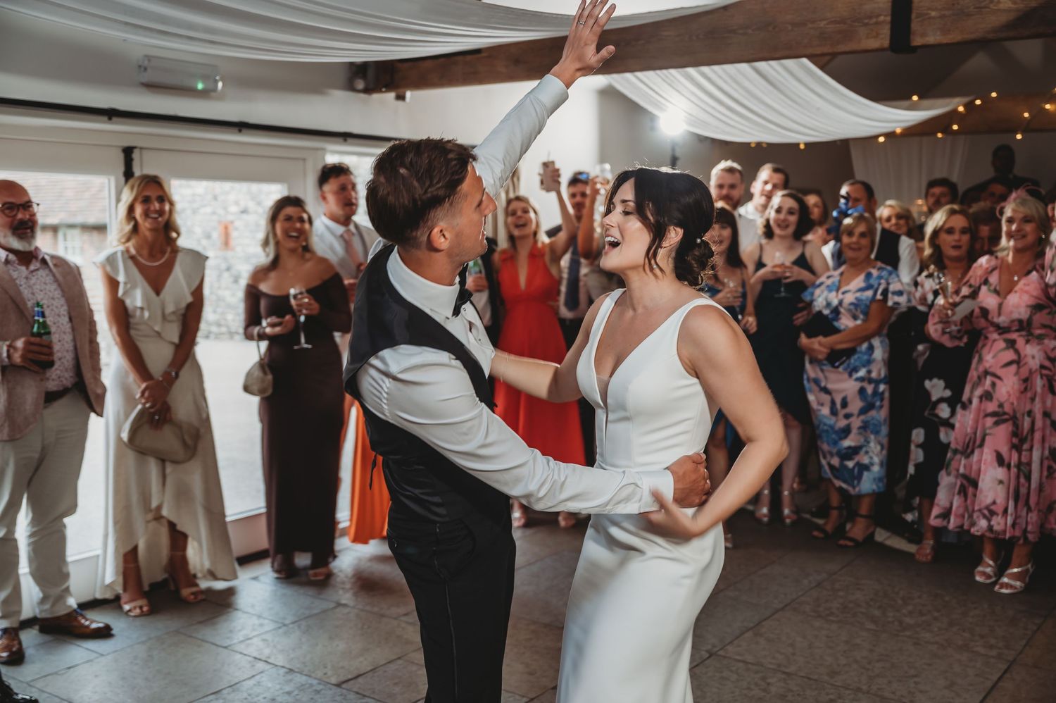 Newlyweds sharing their first dance surrounded by guests at their wedding reception.