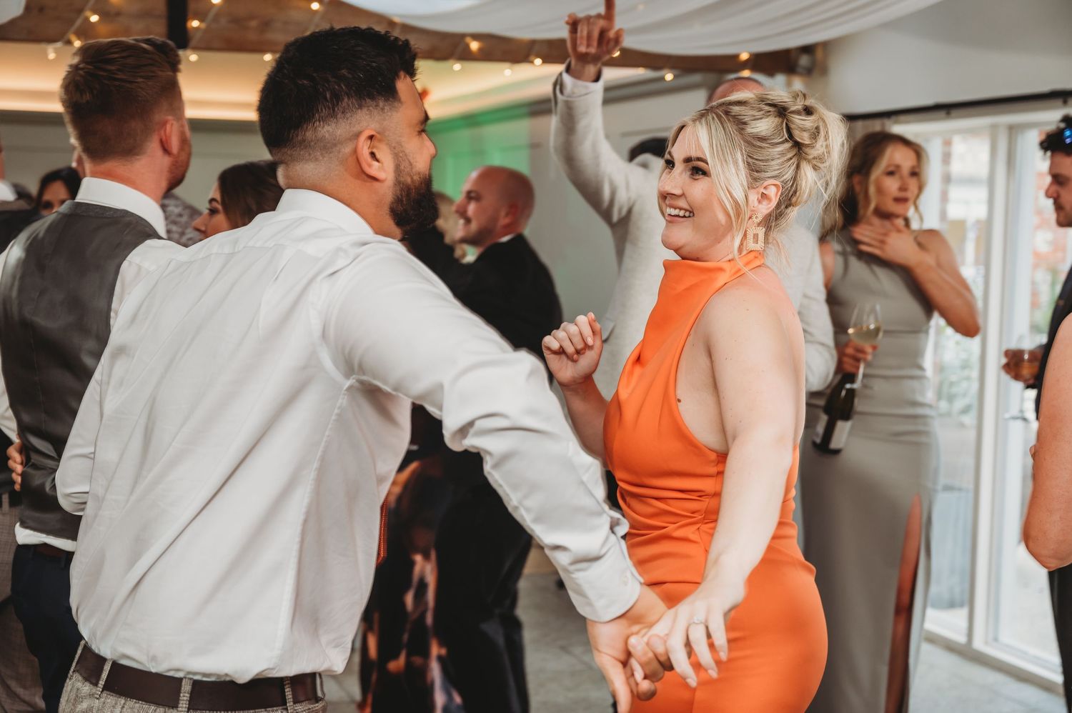 Wedding guests dancing and celebrating on the dance floor at a reception.