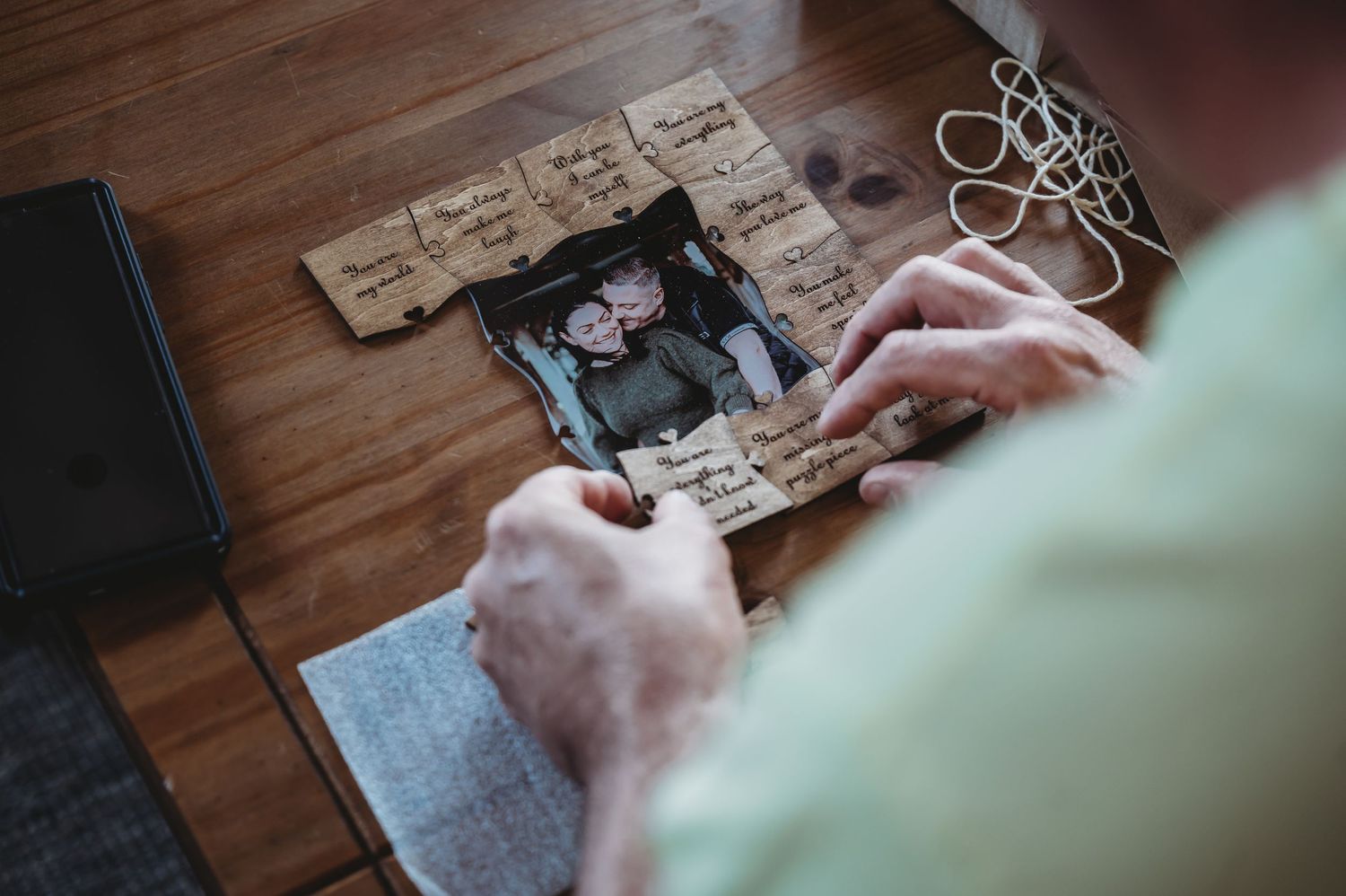 Hands gently hold vintage photograph surrounded by old letters and documents on wooden table.