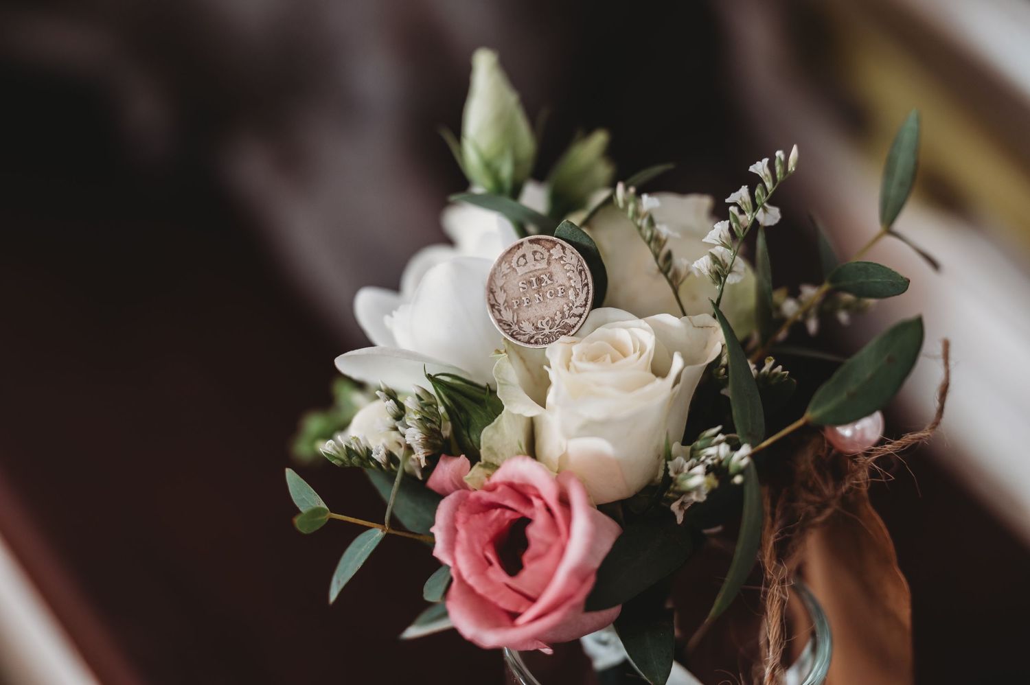 Pink and white roses with delicate greenery arranged in an elegant wedding bouquet detail.