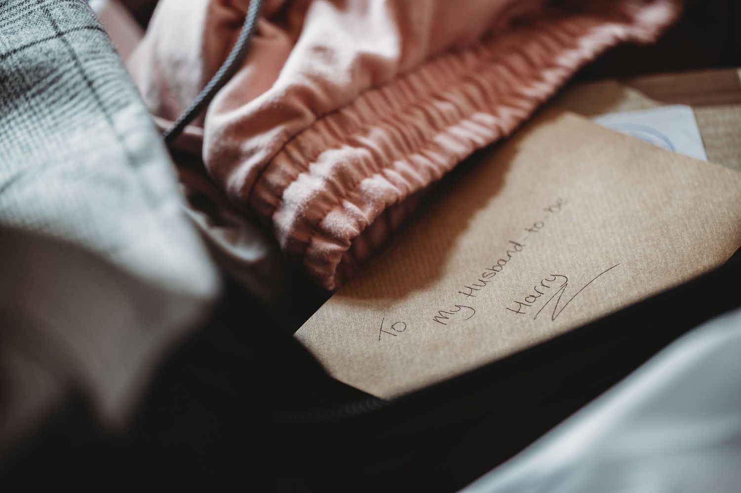 Close-up view of an envelope with handwritten text next to soft pink and gray textured fabrics.