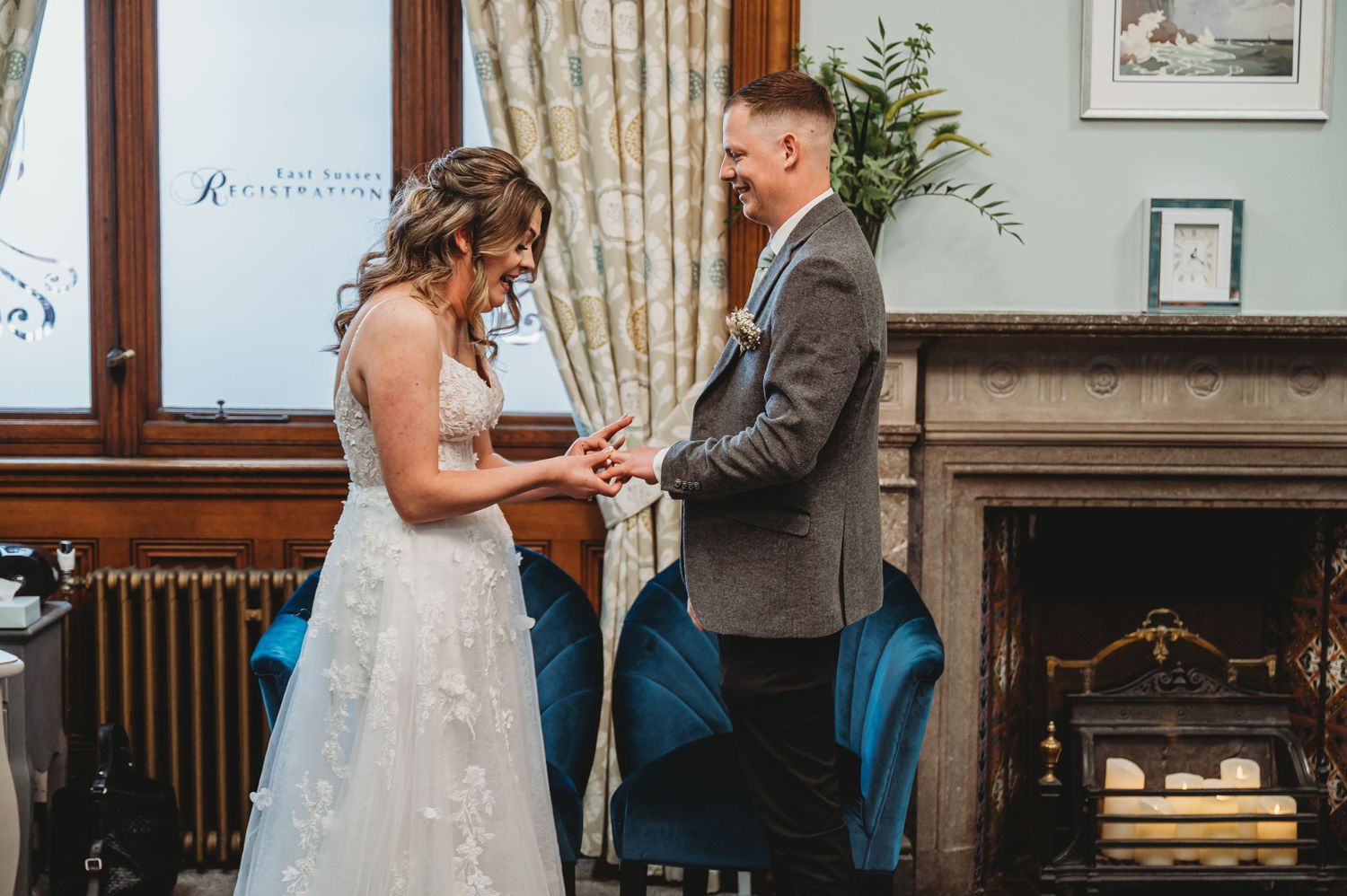 A couple shares a tender moment during their wedding ceremony in an elegant indoor venue with curtained windows.