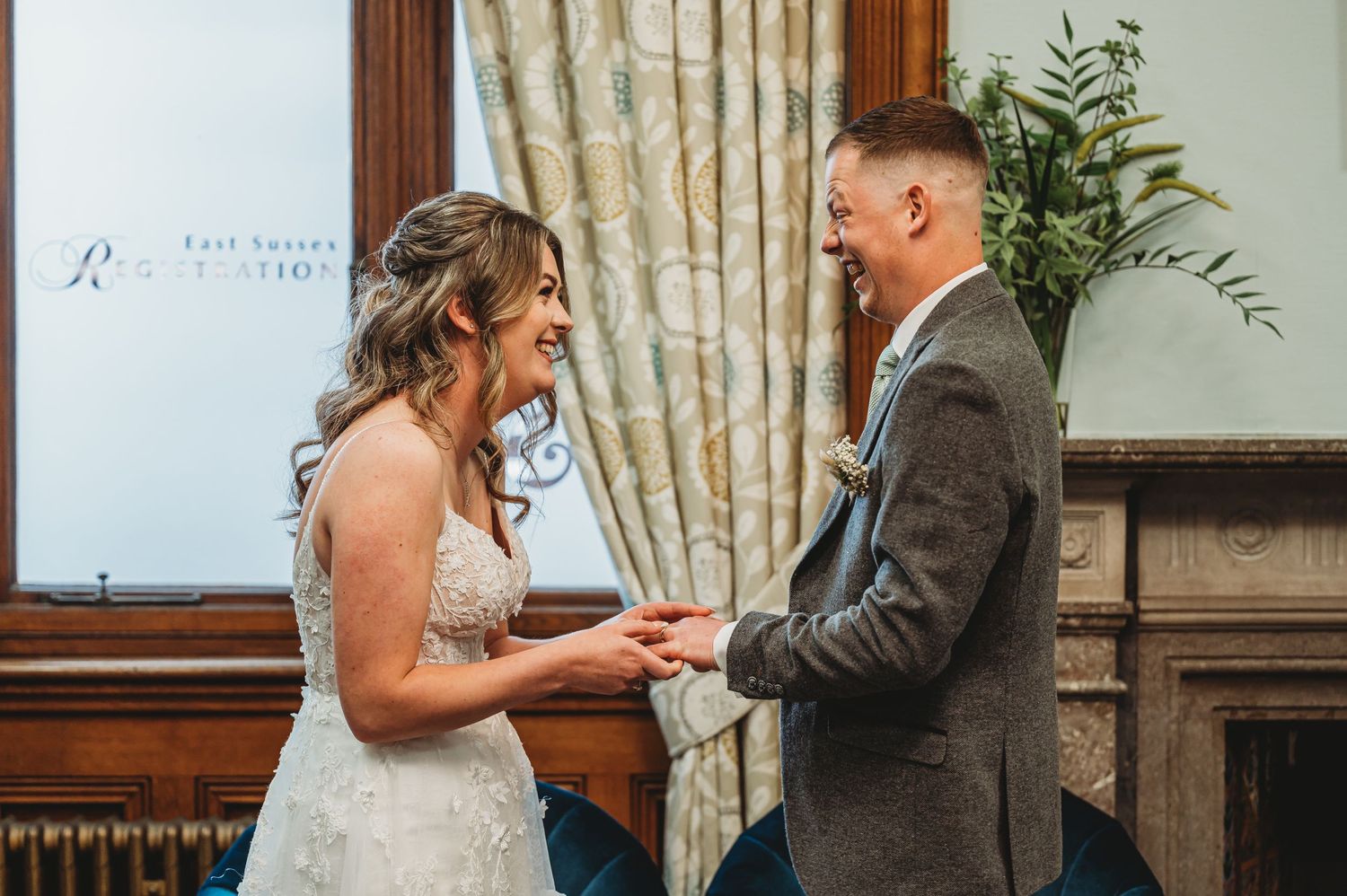 Two people share an intimate moment during their wedding ceremony, clasping hands while dressed in formal attire.
