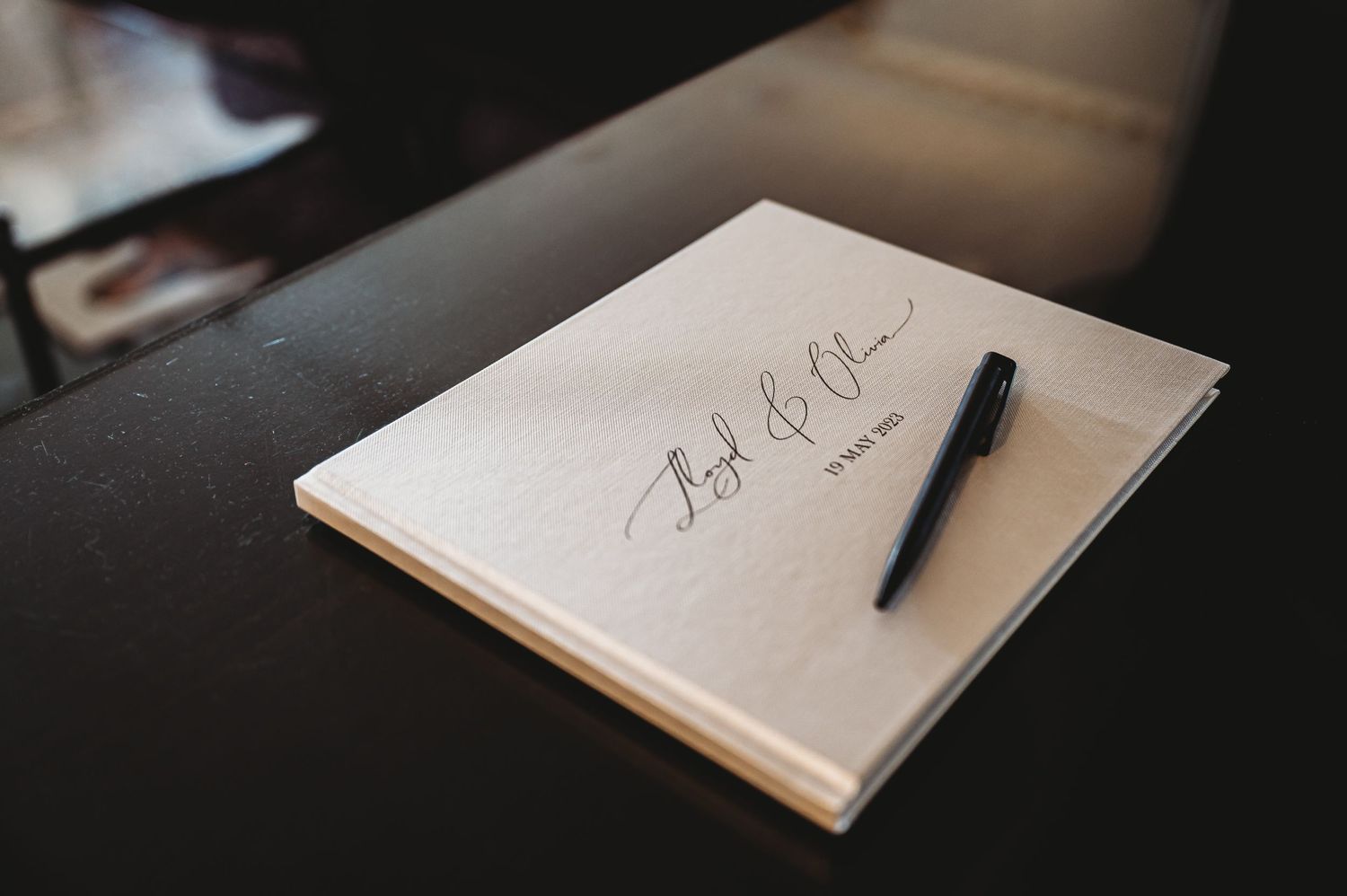 A black pen rests on a light colored notepad with handwritten text on a dark surface.