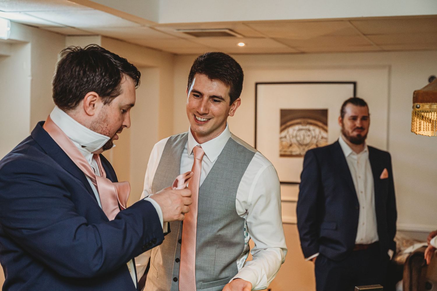 Two people conversing at a formal event while another person stands in the background.