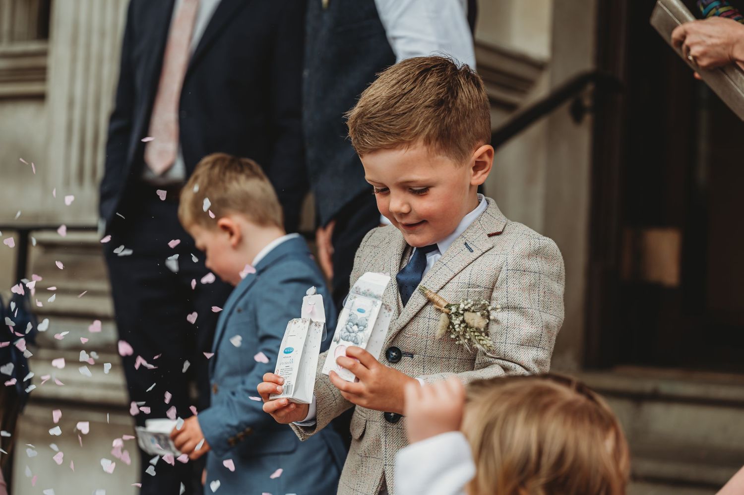 Children play with bubbles while wearing formal attire at an outdoor event.