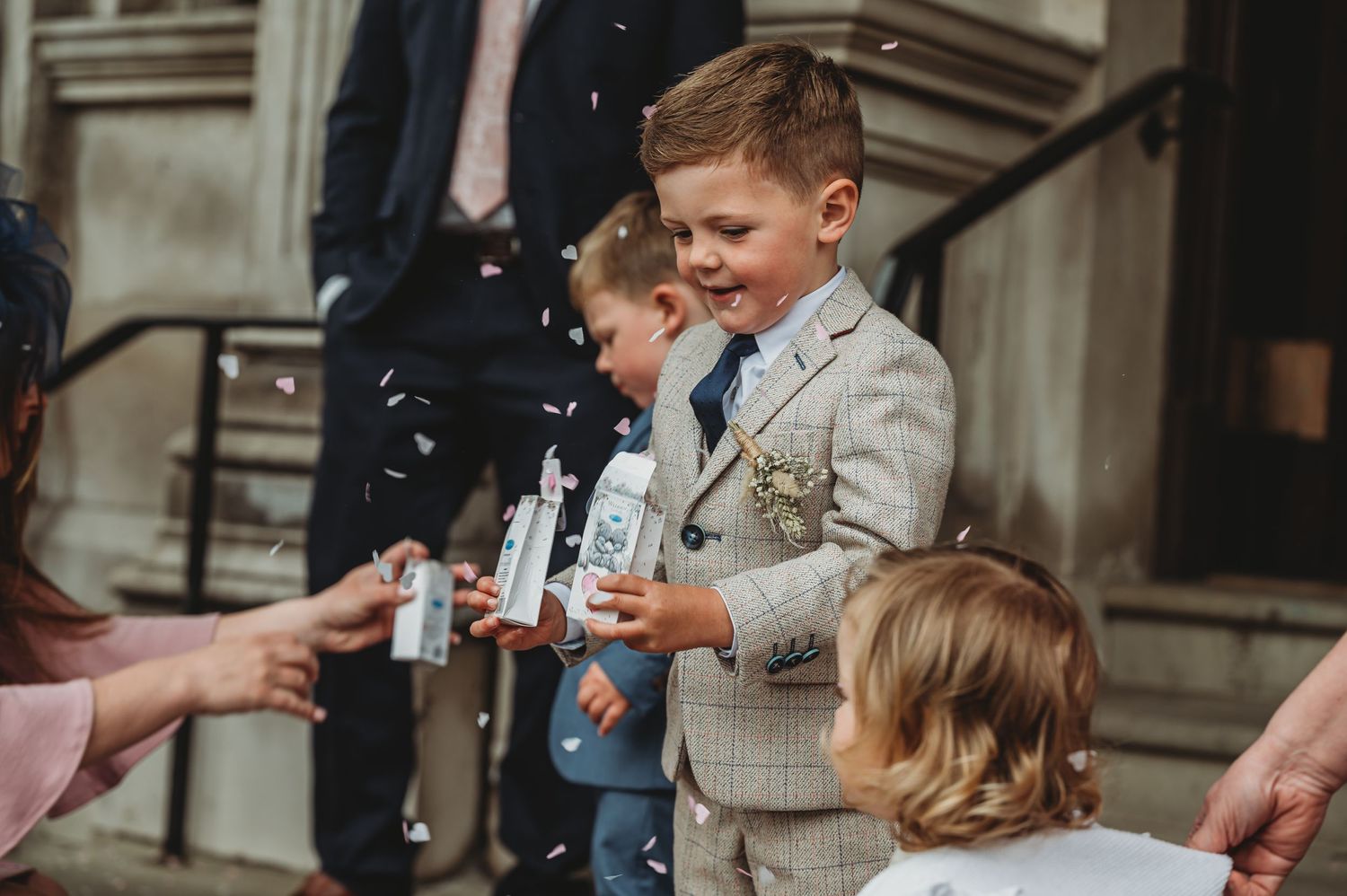 Children stand outside a building while playing with bubbles on a summer day.