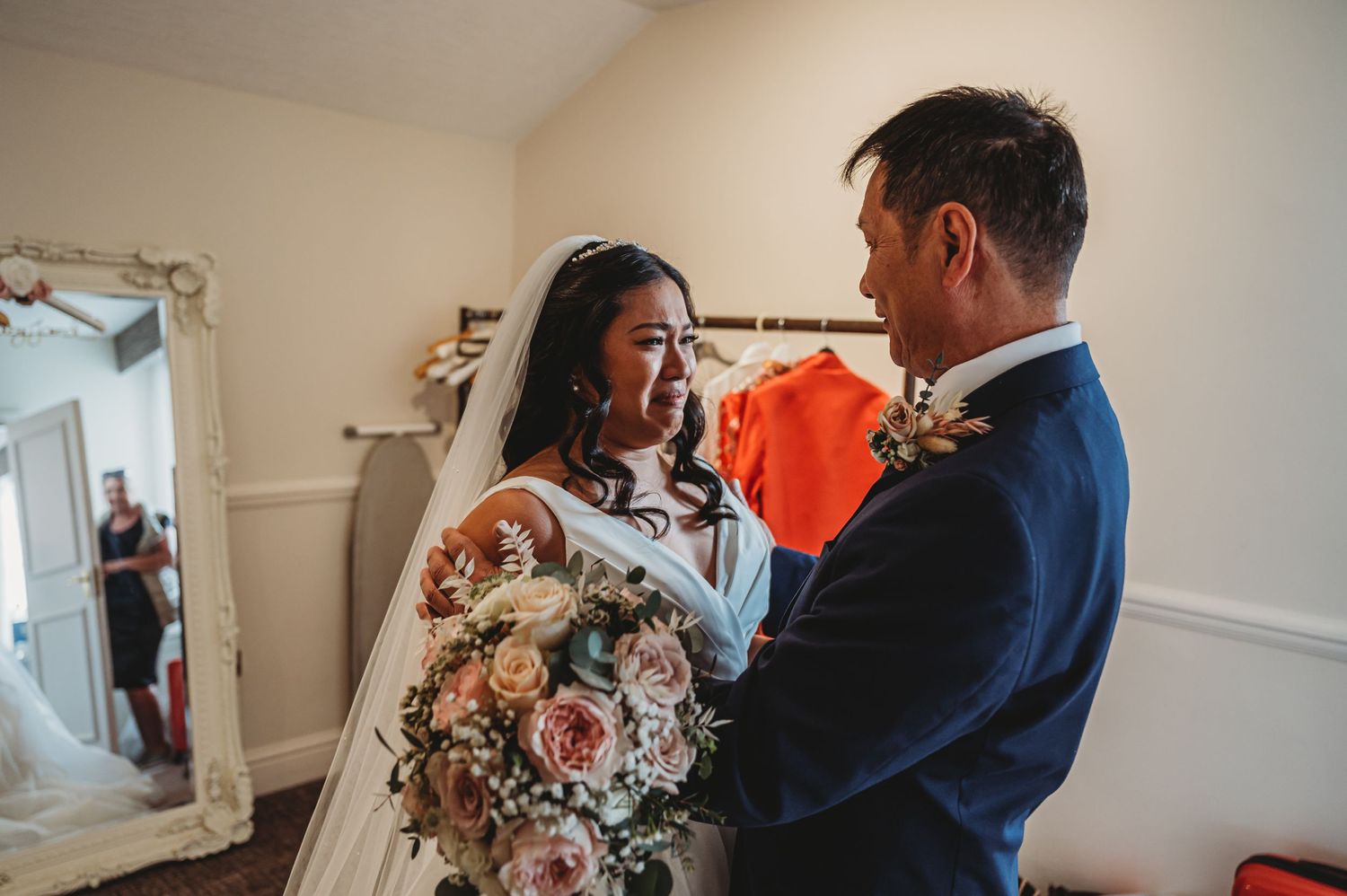 Two people share a tender moment on their wedding day, bride holding a beautiful pastel floral bouquet.