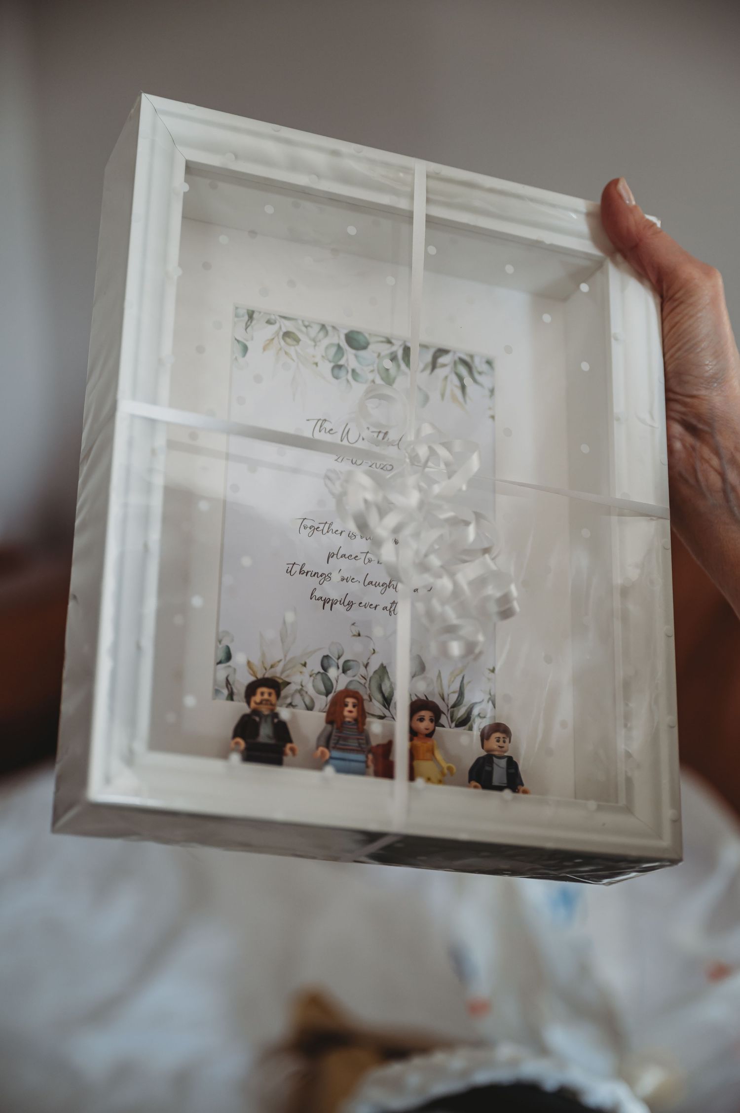 A white display box containing LEGO minifigures with delicate paper decorations and text above them.