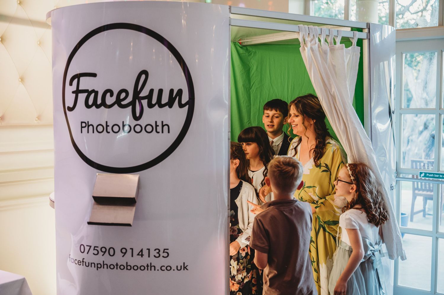 A Facefun photobooth setup with people gathering inside a curtained booth area at an event.