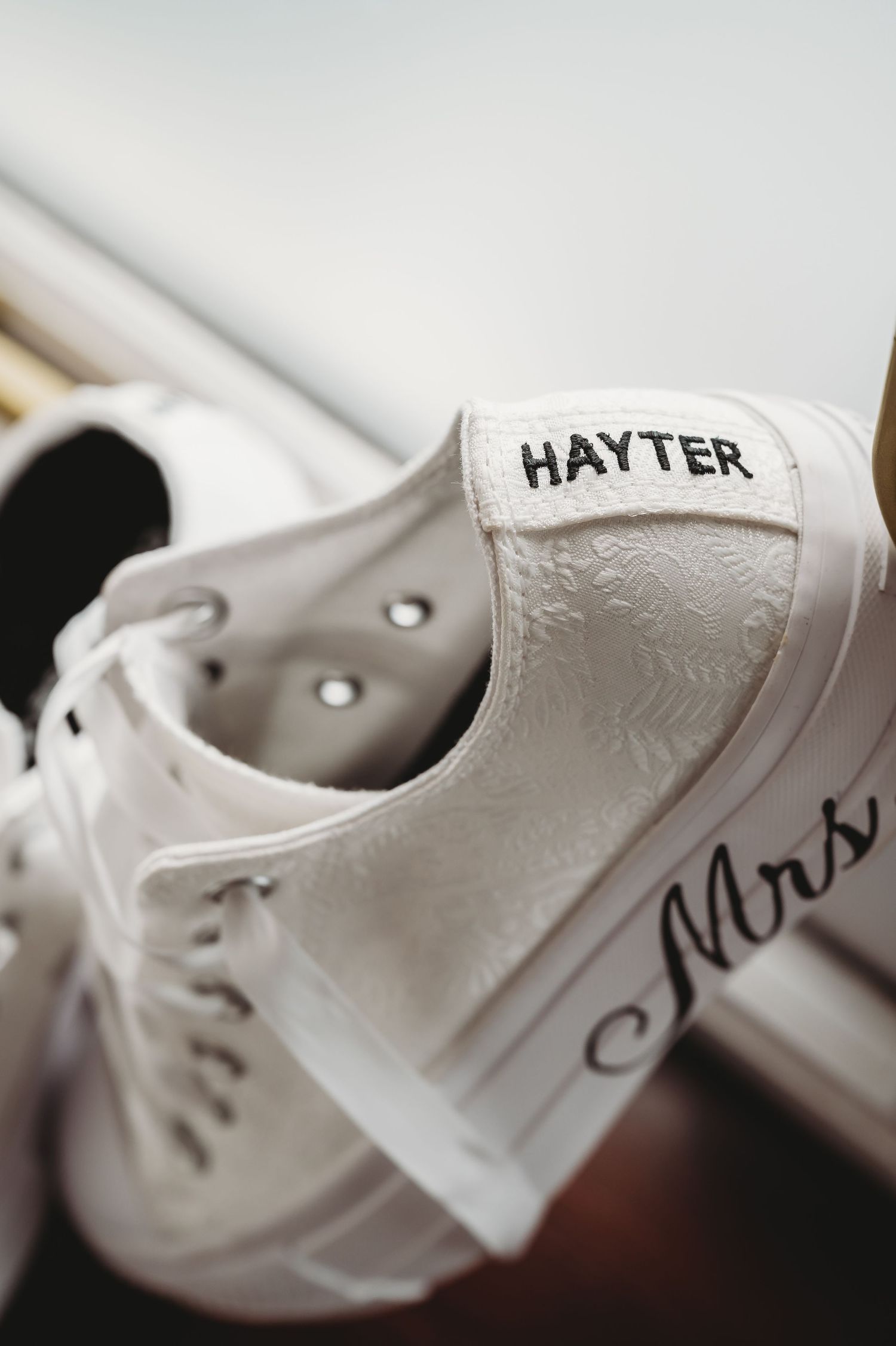 Close-up of a white canvas sneaker showing the Hayter brand name label in crisp detail and embossed pattern texture.