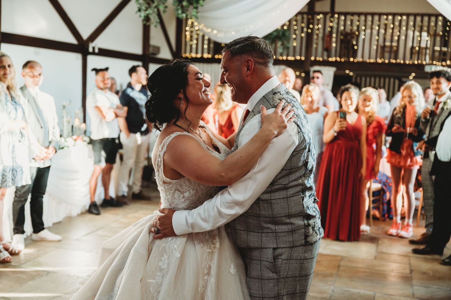 A loving couple shares an intimate dance moment at their wedding reception while wedding guests look on.