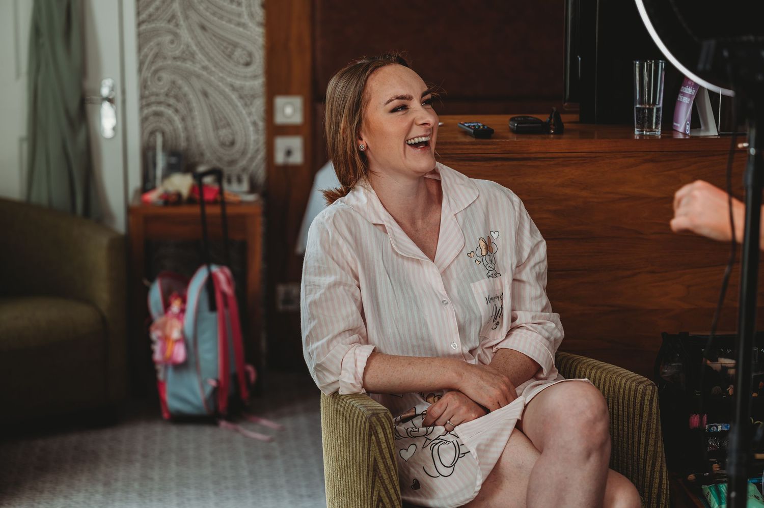 A joyful moment captured in a cozy room with vintage decor as someone laughs while sitting in a green velvet chair.