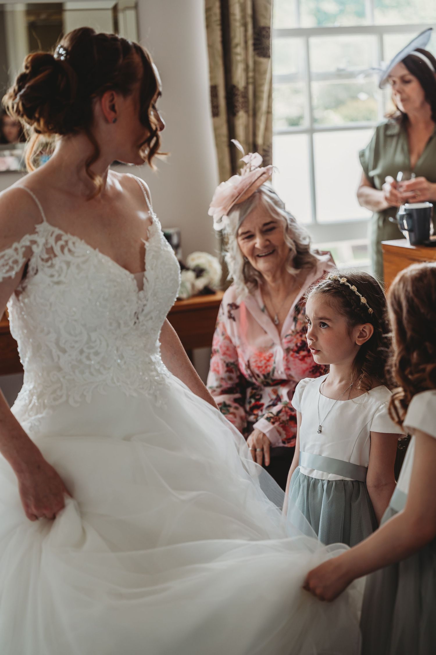 A heartwarming moment shared during wedding preparations as loved ones admire a beautiful white lace gown.