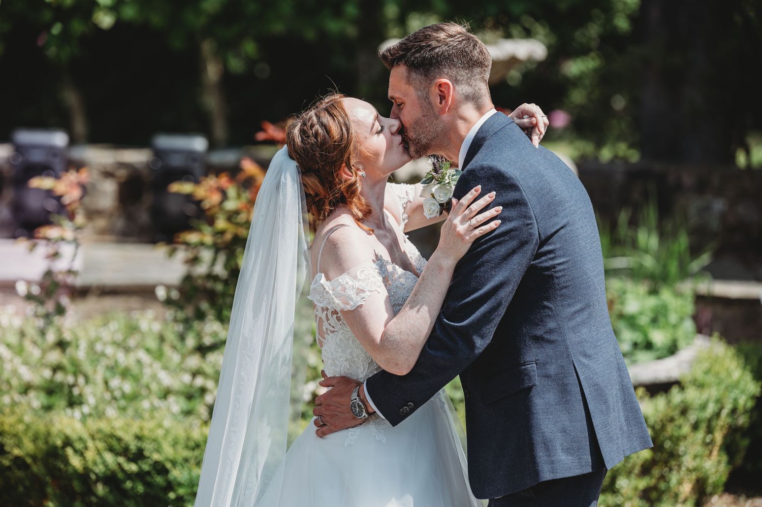 A romantic moment captured between newlyweds in a garden setting with blooming flowers and greenery in the background.
