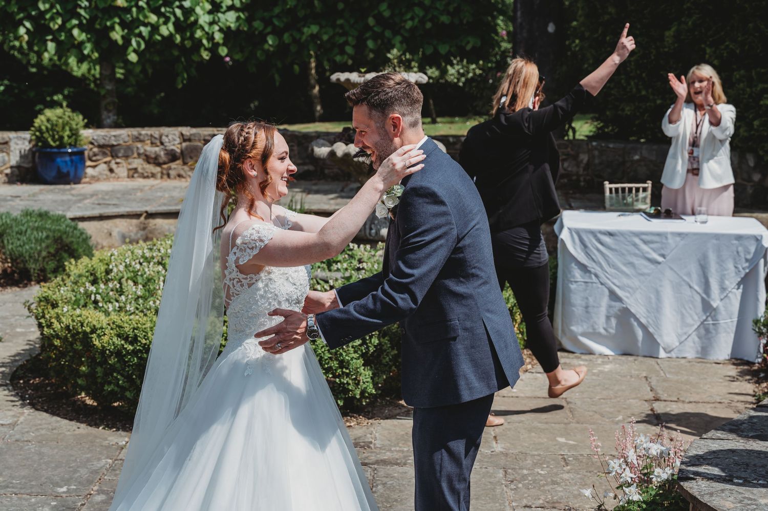 A joyous wedding ceremony taking place outdoors in a garden setting with celebratory gestures and emotions.